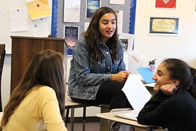 Student in classroom sitting on desk