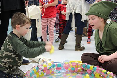 Elementary student playing game with a high school student