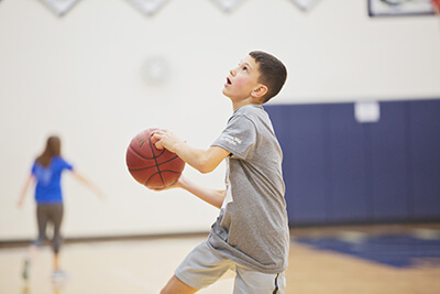 Student in gym playing basketball