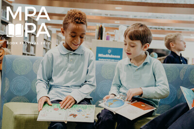 two lower school students reading together in the library