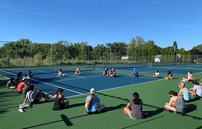 Girls Tennis Team Sitting on Courts