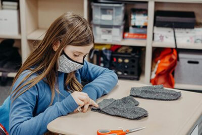 Fourth grader sewing annual mitten project