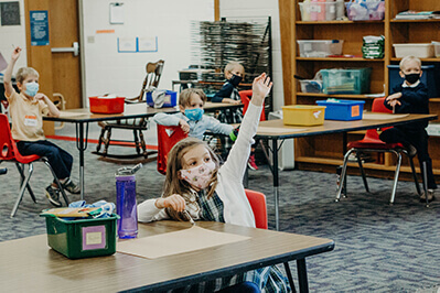 Lower school student raising her hand