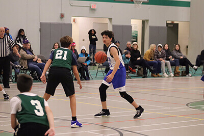 Micah dribbling the basketball vs. Hill Murray