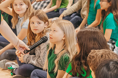 Lower School student talking on microphone at champ assembly