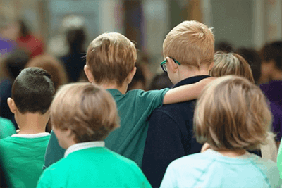 Two students leaving the CHAMP assembly with an arm around the other