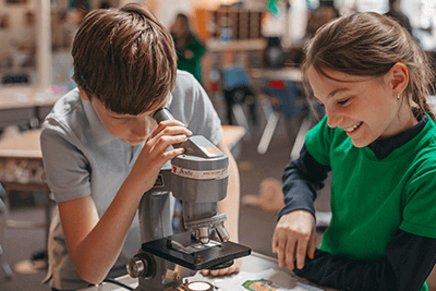 Two Lower School students looking through a microscope. 