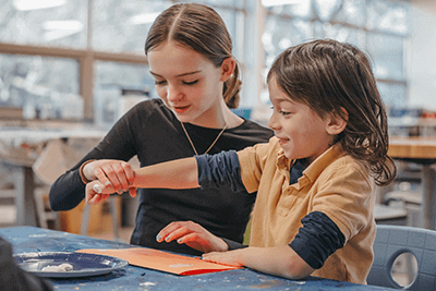 Middle School student works with with Lower School student in the Makerspace. 