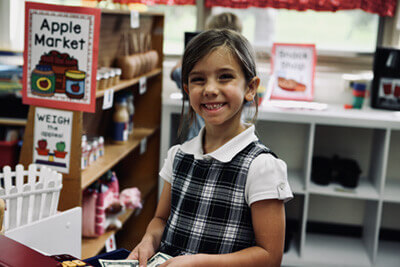 Students playing with play money and cash register at an apple stand