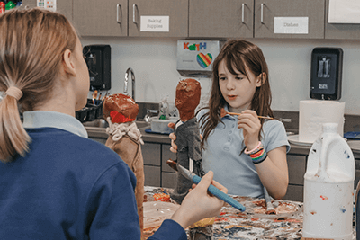 Lower School student working on a soap bottle person. 