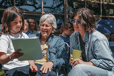 A first-grade student reads poetry to her family. 