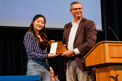 Dr. Bill Hudson, head of school, presents an award to Mina Kim '26 during the US Award Assembly. 