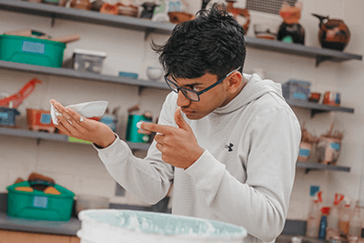 An Upper School students works on his ceramics project. 