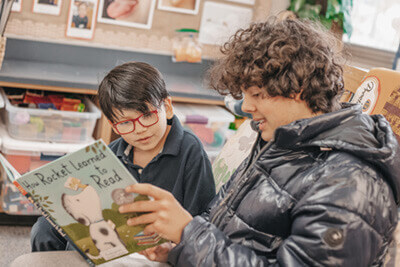 Upper School student reading to a kindergartner