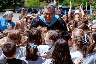 Dr. Bill Hudson, head of school, being embraced by students. 