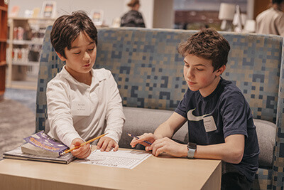 Middle School student working with Lower School student in the Library