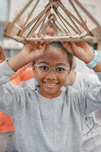 Student holding up a cardboard construction she made at camp