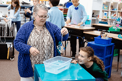 Tami Fisher, second-grade teacher at Mounds Park Academy, shows a students an experiment. 