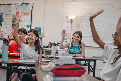 Middle School students raising hands in class