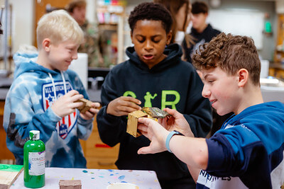 Three boys painting STEM projects.