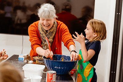 A Lower School student a teacher work together to make a pie.