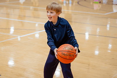 A Lower School student with a basketball in the Lansing Center. 