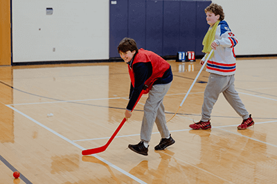 A pair of boys playing floor hockey.