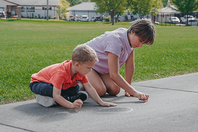 Middle schooler and kindergarten drawing with chalk