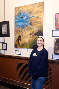 A student posing with her painting. 