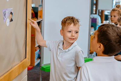 A student pointing at a board and smiling.