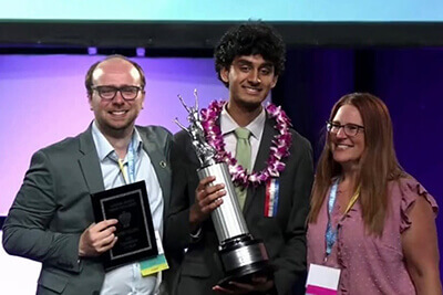Student smiling and holding an award.